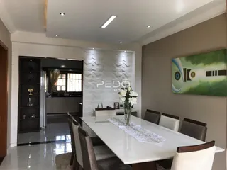 Uma sala de jantar moderna com mesa branca e cadeiras em um imóvel no Brasil.