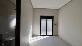 Hall de entrada com paredes brancas e porta escura.