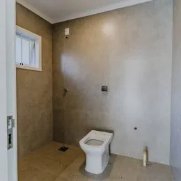 Foto de um banheiro com paredes de cor neutra e um vaso sanitário branco.