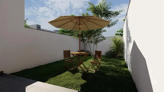 Jardim gramado com uma mesa e cadeiras sob uma guarda-sol.