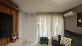 Sala de estar com televisão e cortinas brancas.