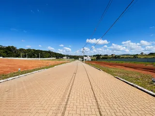 Uma estrada pavimentada se estende por um campo aberto sob um céu azul.
