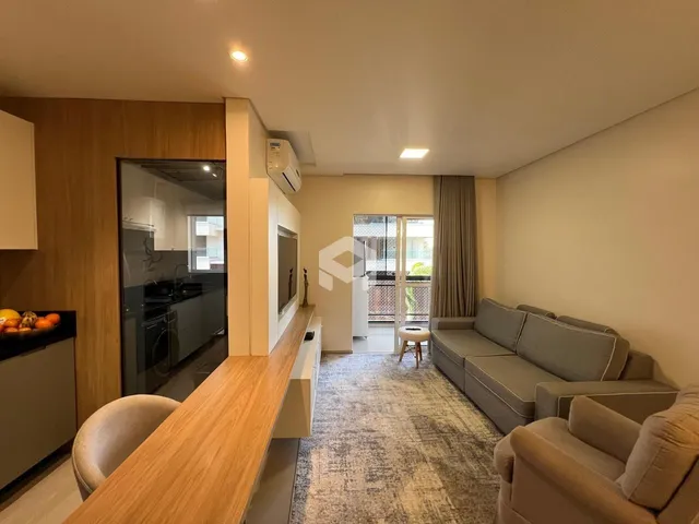 Sala de estar com sofá e área de jantar em um apartamento em Lajeado.