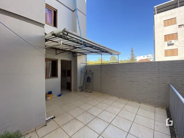 Área externa pavimentada com piso de cerâmica e estrutura de telhado metálico.
