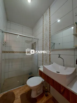 Foto de um banheiro com box de vidro e piso de madeira.