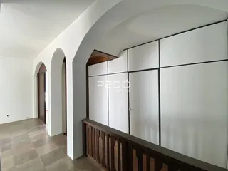 Corredor interno com piso de cerâmica e grade de madeira.