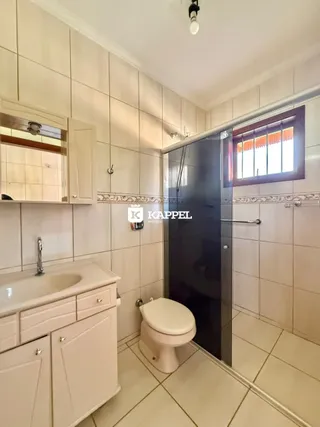 Banheiro com revestimento de azulejos brancos e bancada de pia.