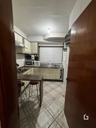 Vista interna de uma cozinha com armários e piso de cerâmica.