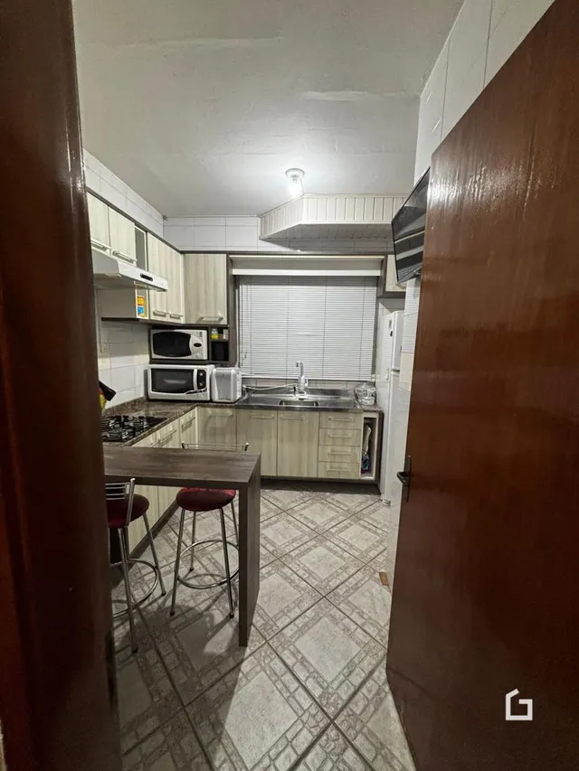 Vista interna de uma cozinha com armários e piso de cerâmica.