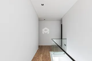Hall de entrada com piso de madeira e escada de vidro.