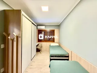 Quarto com armários em madeira e cama com roupa de cama verde.