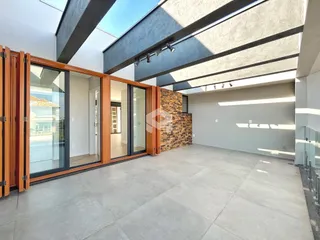 Ambiente interno de uma sala ampla com piso de grande formato e portas de vidro.