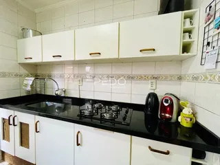 Cozinha com armários brancos e bancada preta.