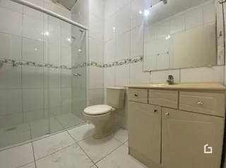 A foto mostra o interior de um banheiro com piso e paredes brancas.