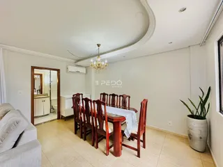 Uma sala de jantar com mesa de madeira e cadeiras.