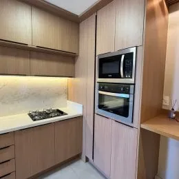 Foto de uma cozinha com armários de madeira clara e bancada.