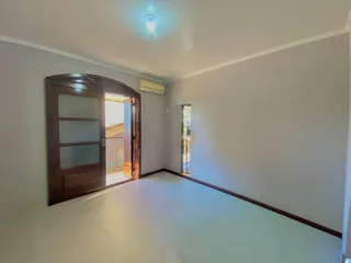Hall de entrada com piso claro e porta de madeira que dá acesso a uma área externa.