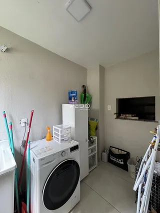 Interior de uma área de serviço com máquina de lavar e prateleiras.