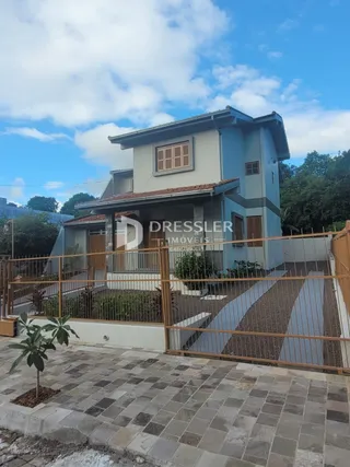Fachada de uma residência em Lajeado, Brasil, com cerca e paisagismo na frente.