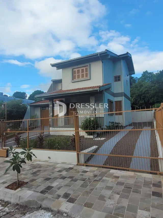 Fachada de uma residência em Lajeado, Brasil, com cerca e paisagismo na frente.