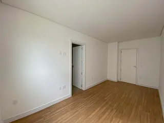 Hall de entrada com piso de madeira clara e paredes brancas.