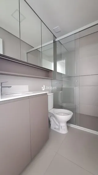 Banheiro moderno com box de vidro e revestimento claro.