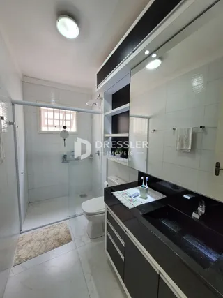 Interior de um banheiro moderno com piso de cerâmica e box de vidro.