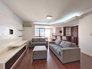 Sala de estar com sofá e piso de madeira em um apartamento.