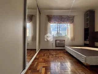 Quarto com piso de madeira e janela com vista para a cidade.