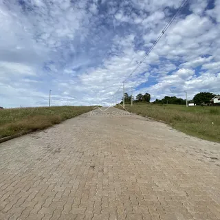 Vista de uma estrada pavimentada em uma área rural com vegetação ao redor.