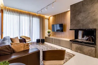 Sala de estar moderna com lareira e grandes janelas em Lajeado.