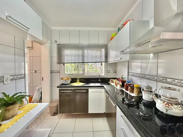 Esta é uma foto da cozinha de uma residência com armários brancos e bancadas escuras.