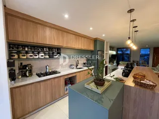 Cozinha com armários de madeira e bancadas claras em um imóvel no Brasil.