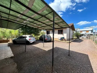 Área externa coberta com estrutura de pergolado em frente a uma residência.