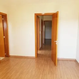 Vista de um corredor com piso de madeira clara.