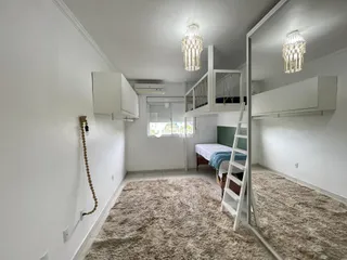 Quarto com decoração clara e piso felpudo.