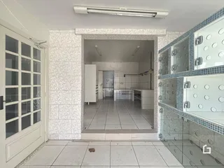 Corredor com paredes revestidas de azulejos levando a uma área interna.