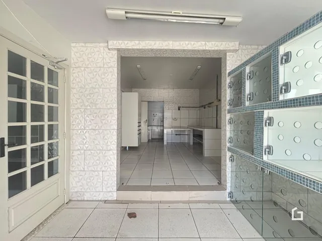 Corredor com paredes revestidas de azulejos levando a uma área interna.
