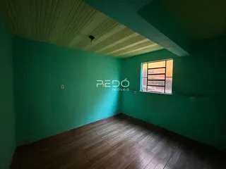 Ambiente interno de uma sala com piso de madeira e parede verde-água.