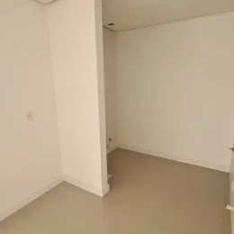 Espaço interno com paredes brancas e piso claro.