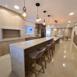 Cozinha moderna com ilha central e banquetas em um ambiente claro.