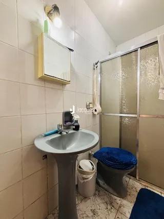 Banheiro com revestimento cerâmico e louças sanitárias.