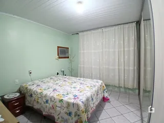 Quarto com paredes verdes e janela coberta por cortinas brancas.