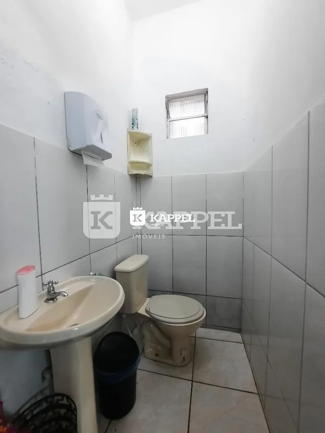 Foto de um banheiro com pia e vaso sanitário revestido de azulejos brancos.