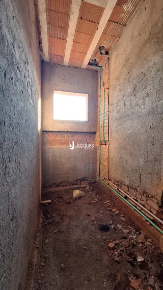 Corredor interno com paredes de alvenaria exposta e piso de terra.