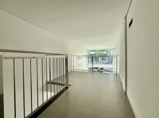 Um corredor interno com piso de cerâmica e guarda-corpo de metal.