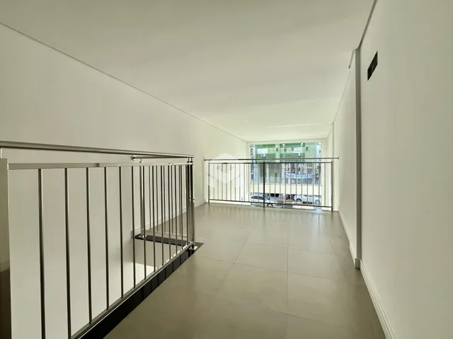 Um corredor interno com piso de cerâmica e guarda-corpo de metal.