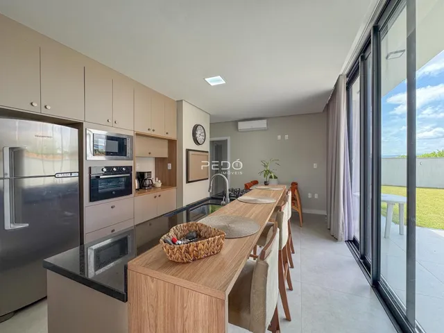 Vista de uma cozinha e sala de jantar moderna com portas de vidro que dão para o exterior.