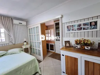 Quarto com cama de casal e janela com cortinas brancas.