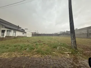 Vista externa de um terreno gramado com cerca no fundo.